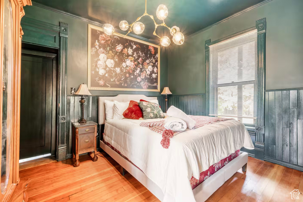 Bedroom with crown molding, wooden walls, and wood-type flooring