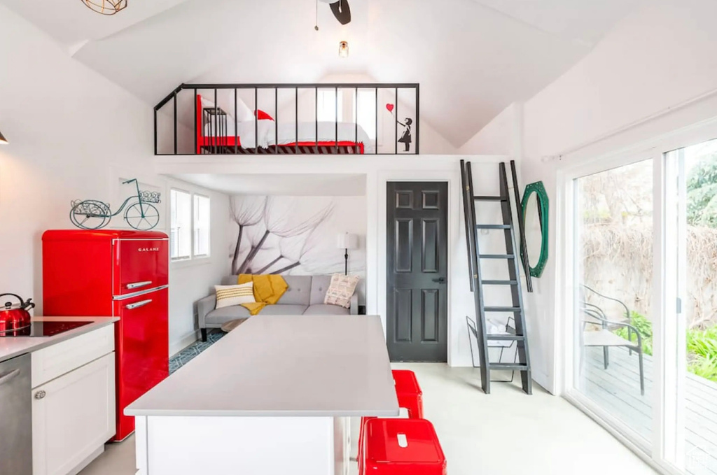 Carpeted bedroom featuring lofted ceiling, fridge, multiple windows, and access to outside