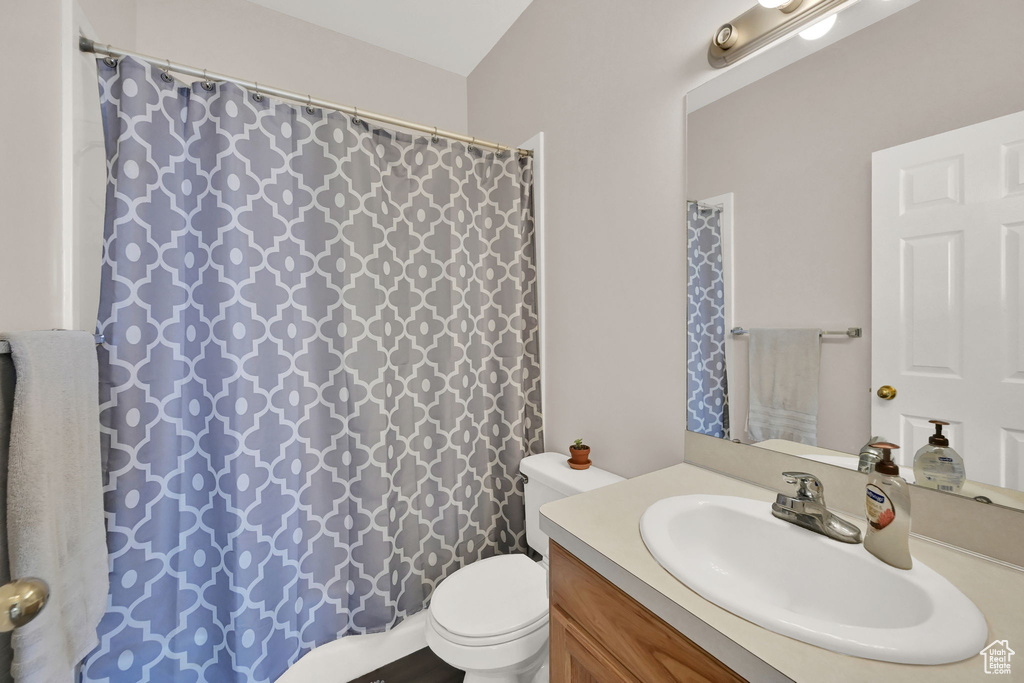 Bathroom featuring vanity, curtained shower, and toilet