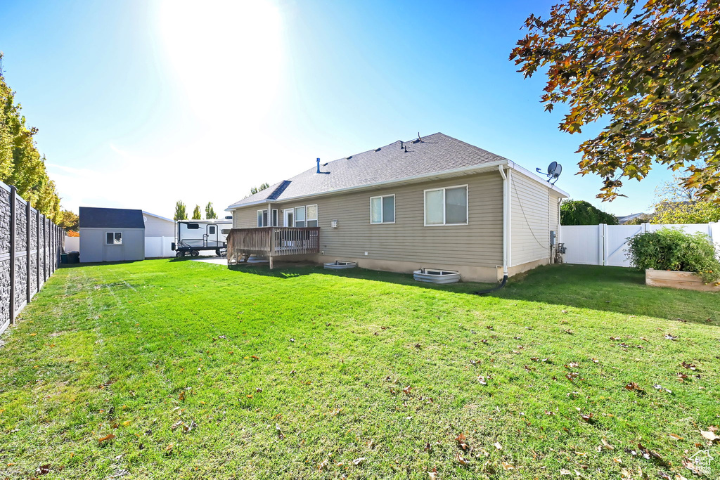 Rear view of property with a wooden deck, a yard, and a shed