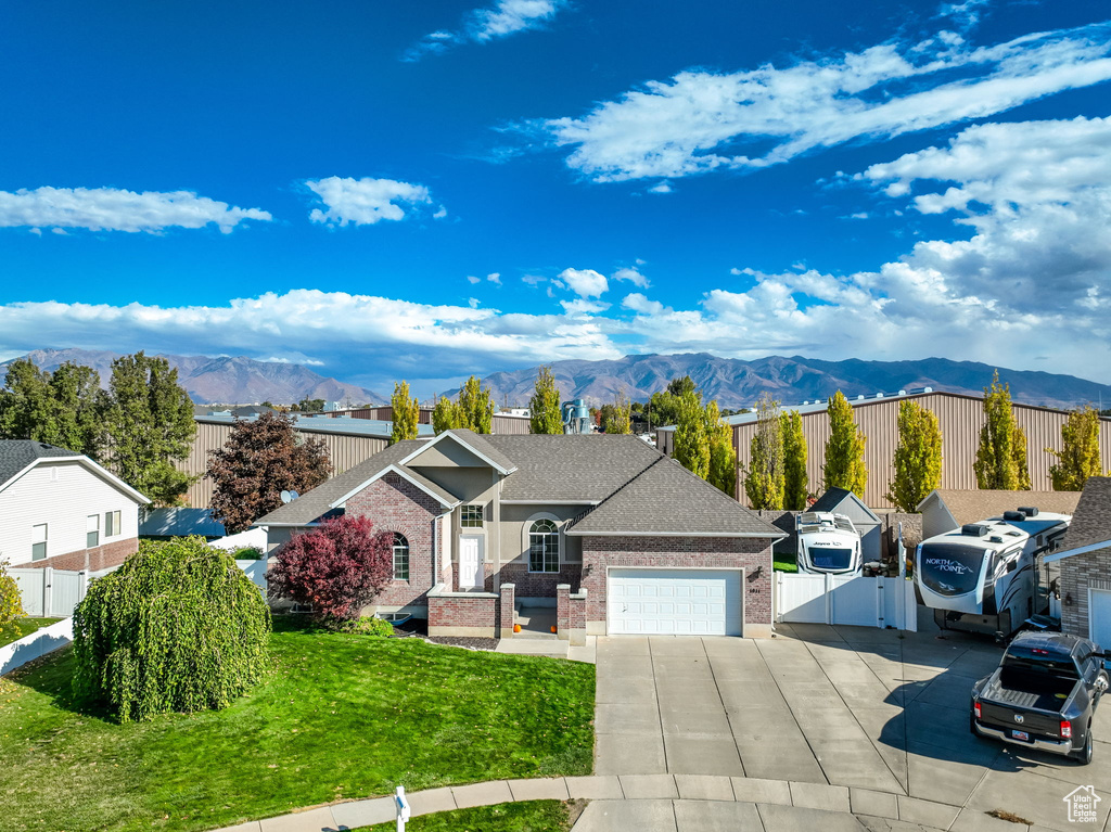 Ranch-style house with a garage, a mountain view, and a front lawn