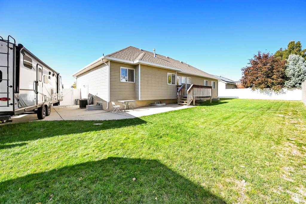 Back of house with a deck, a patio area, and a lawn