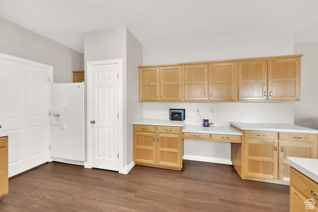 Kitchen featuring built in desk, white refrigerator with ice dispenser, light brown cabinetry, and dark hardwood / wood-style flooring