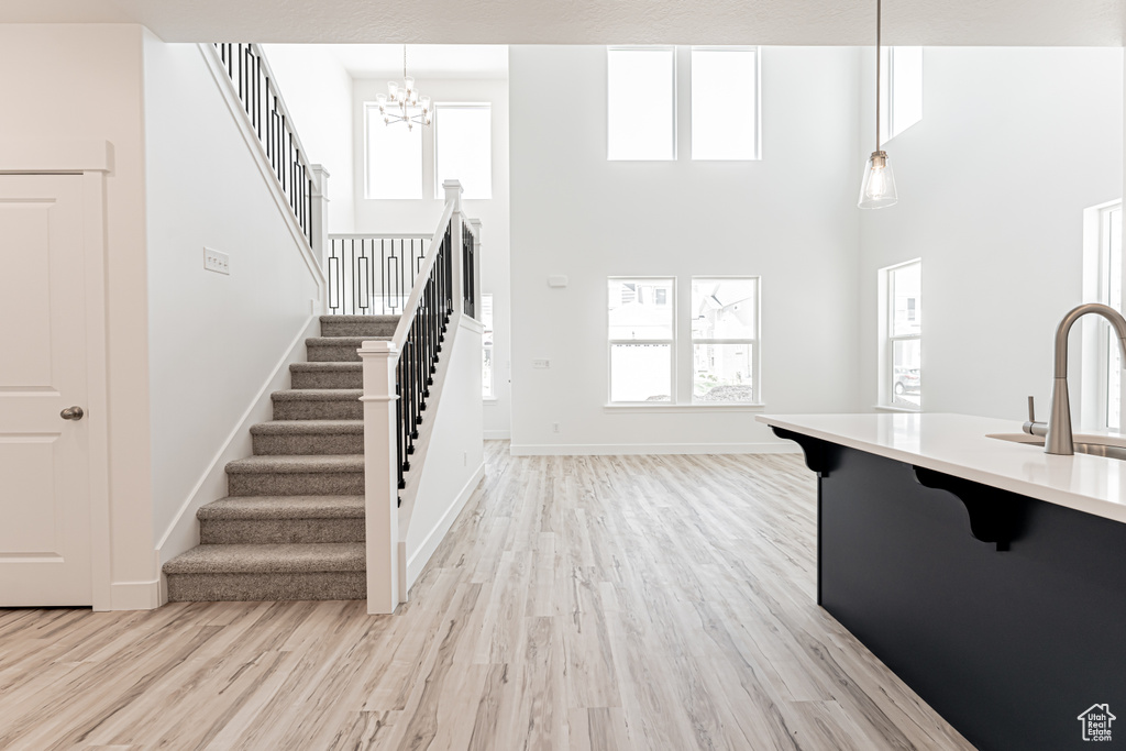 Kitchen featuring a breakfast bar area, light wood-style floors, a chandelier, light countertops, and a high ceiling