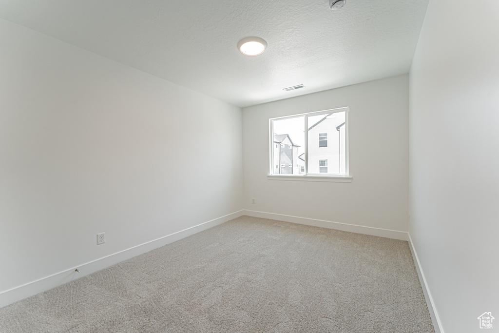 Spare room featuring light carpet and a textured ceiling