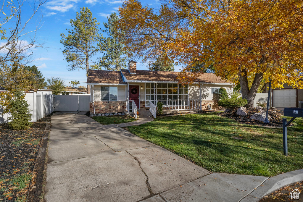 Ranch-style house featuring covered porch and a front lawn