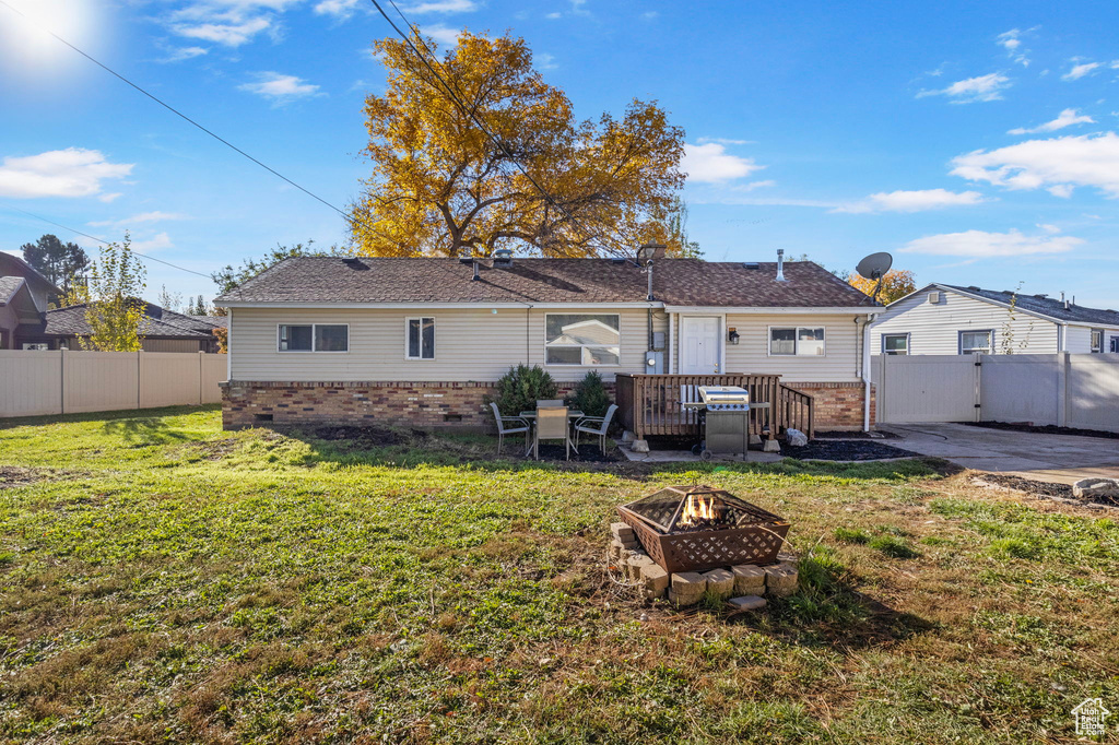 Rear view of property featuring a fire pit and a lawn