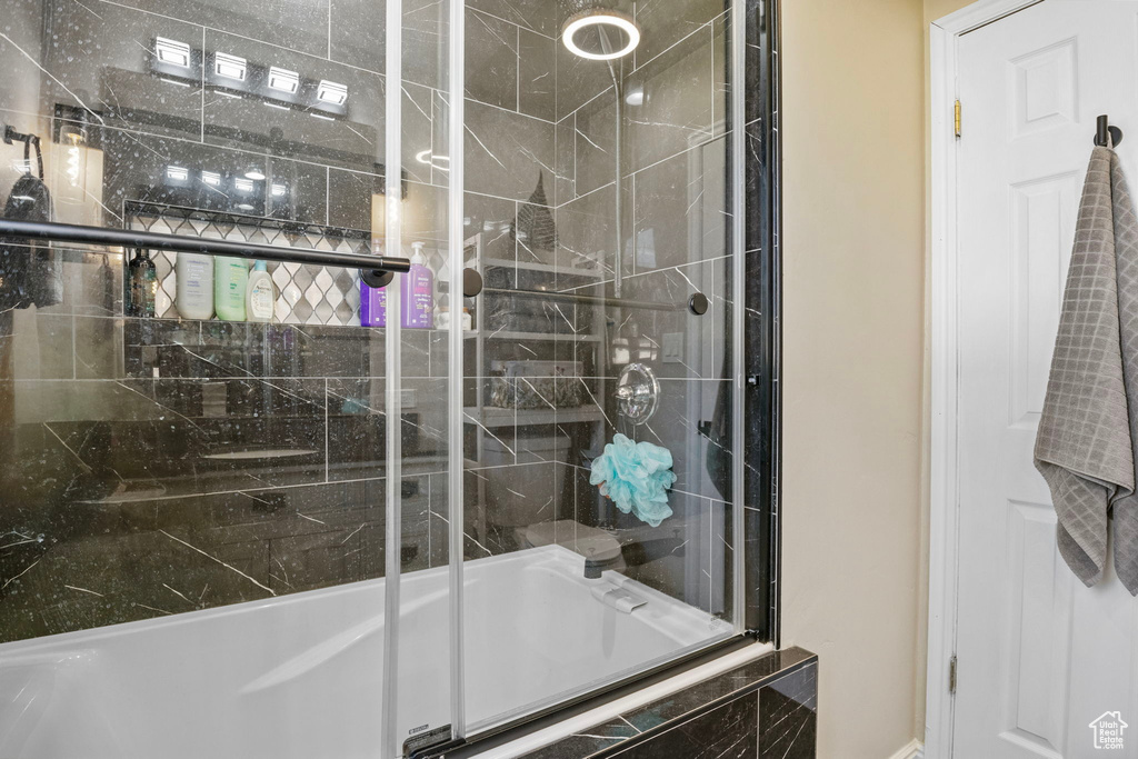 Bathroom featuring combined bath / shower with glass door