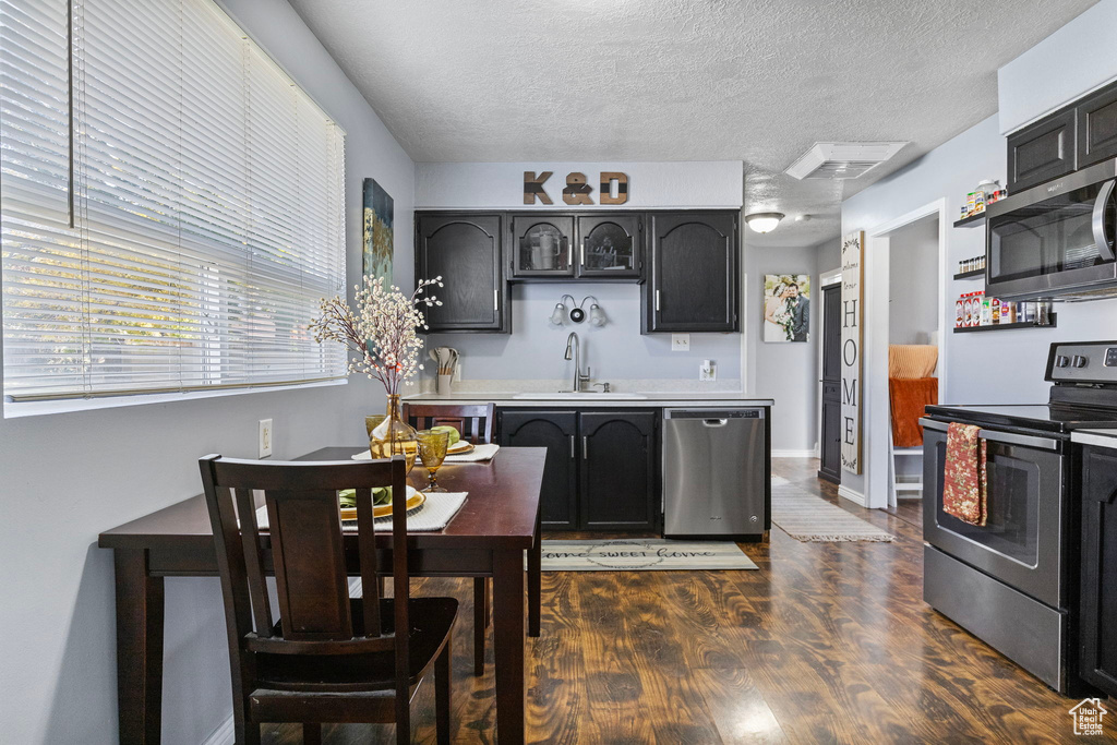 Kitchen with sink, dark wood-type flooring, stainless steel appliances, and a textured ceiling