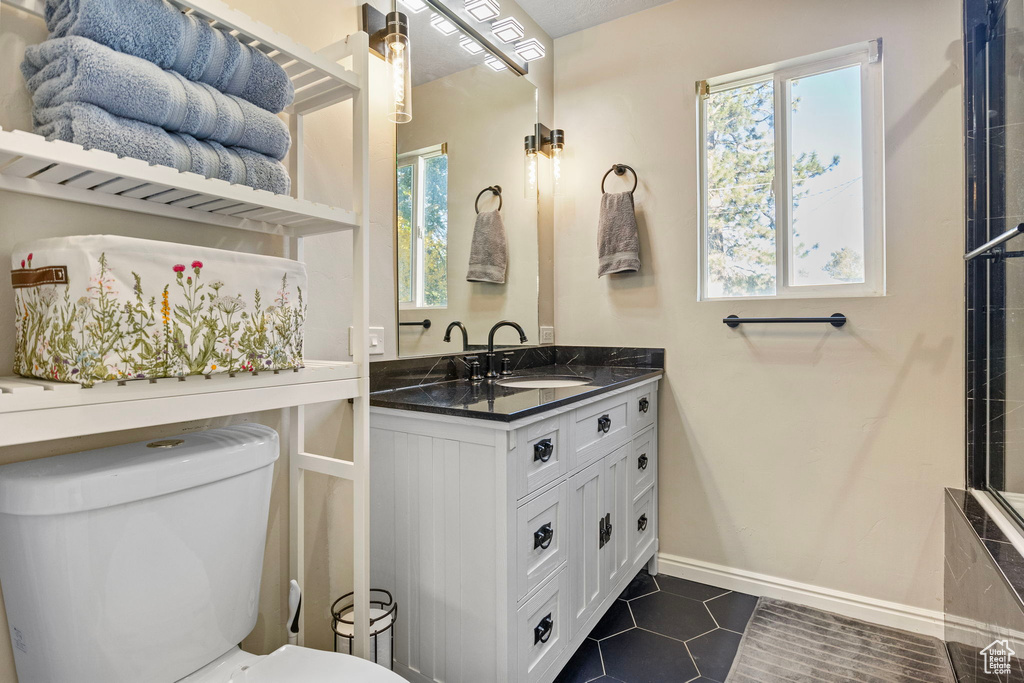 Bathroom featuring toilet, tile patterned flooring, and a wealth of natural light