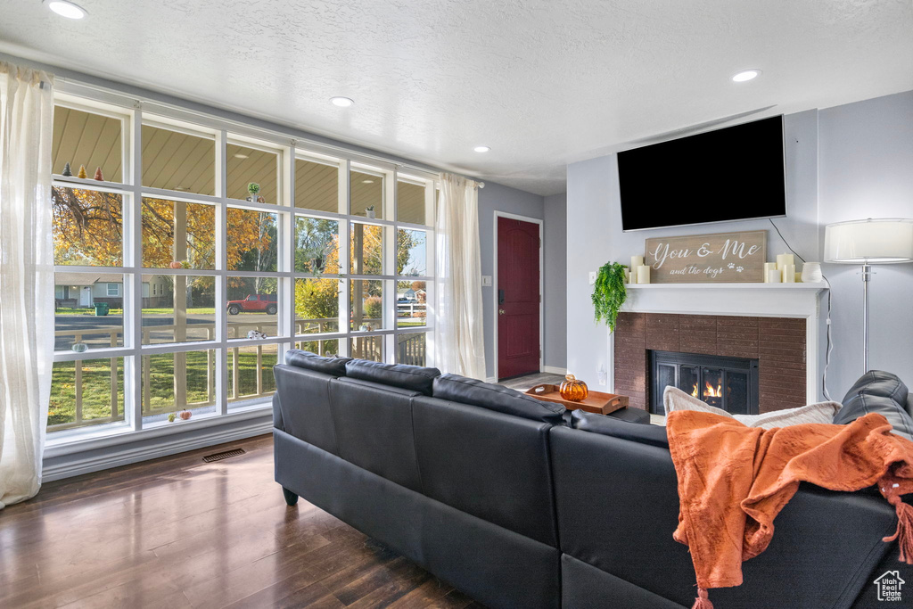 Living room featuring a tile fireplace, a textured ceiling, dark hardwood / wood-style floors, and a healthy amount of sunlight