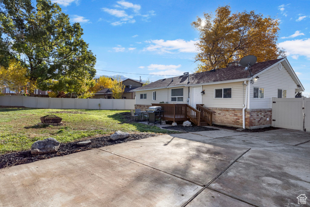 Rear view of property featuring a patio area, an outdoor fire pit, a deck, and a lawn