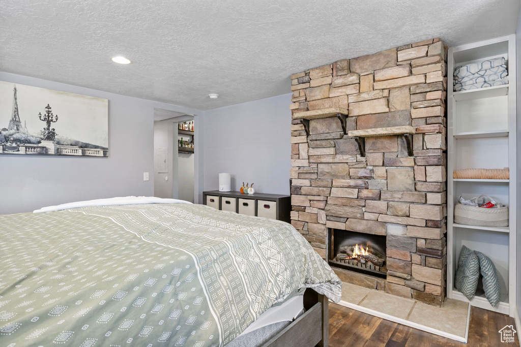 Bedroom with a textured ceiling, dark hardwood / wood-style flooring, and a fireplace