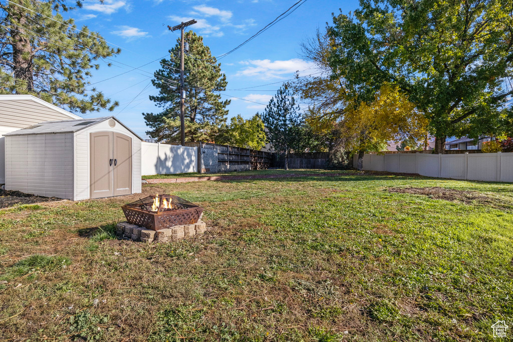 View of yard with a storage unit and a fire pit