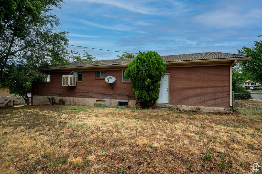 Back of property with a yard and an AC wall unit