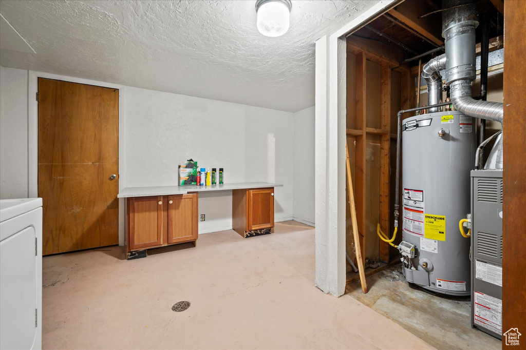 Basement with washer / clothes dryer, a textured ceiling, and water heater