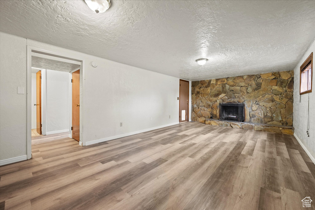 Unfurnished living room with light hardwood / wood-style floors, a textured ceiling, and a fireplace