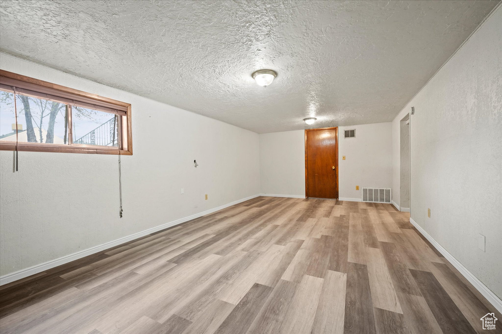 Unfurnished room with light hardwood / wood-style floors and a textured ceiling