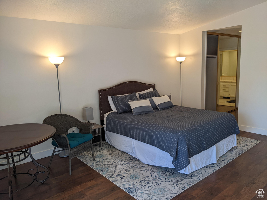 Bedroom with connected bathroom and dark wood-type flooring