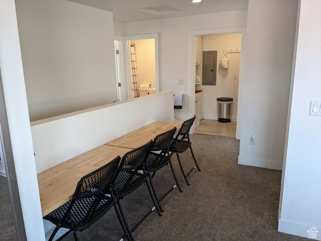 Dining space featuring electric panel and dark colored carpet
