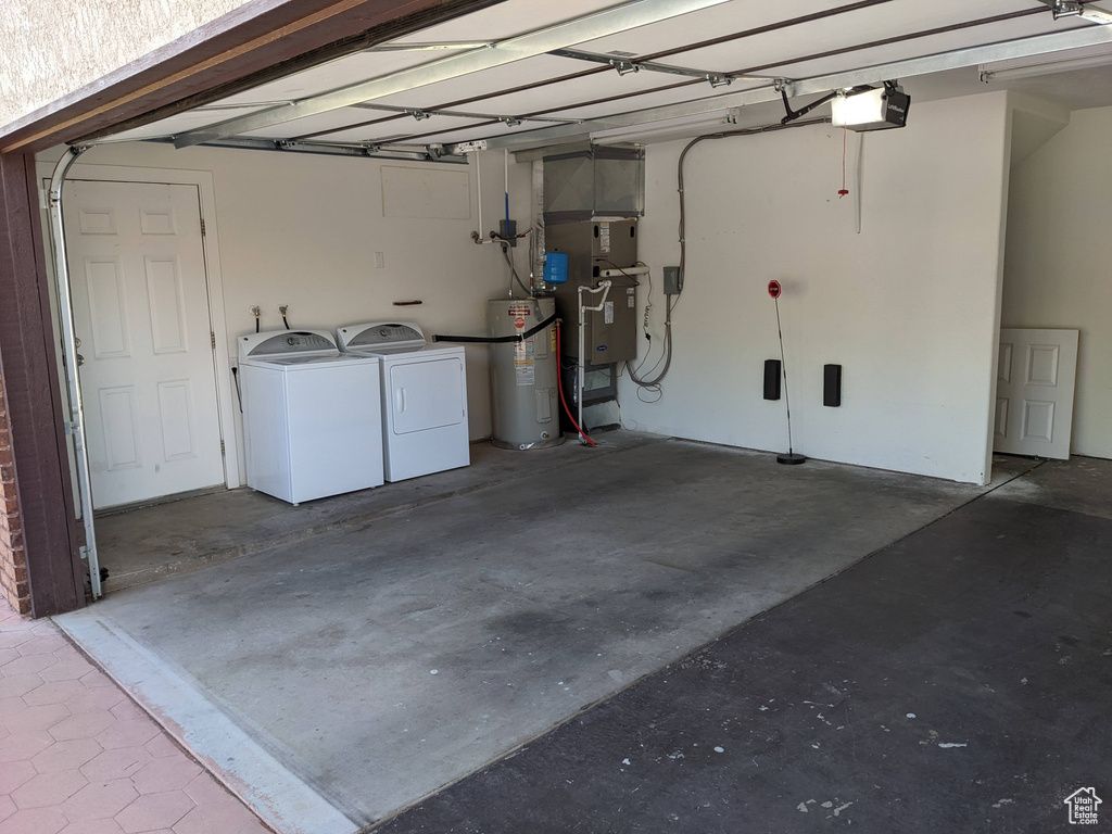 Garage featuring a garage door opener, water heater, heating unit, and separate washer and dryer