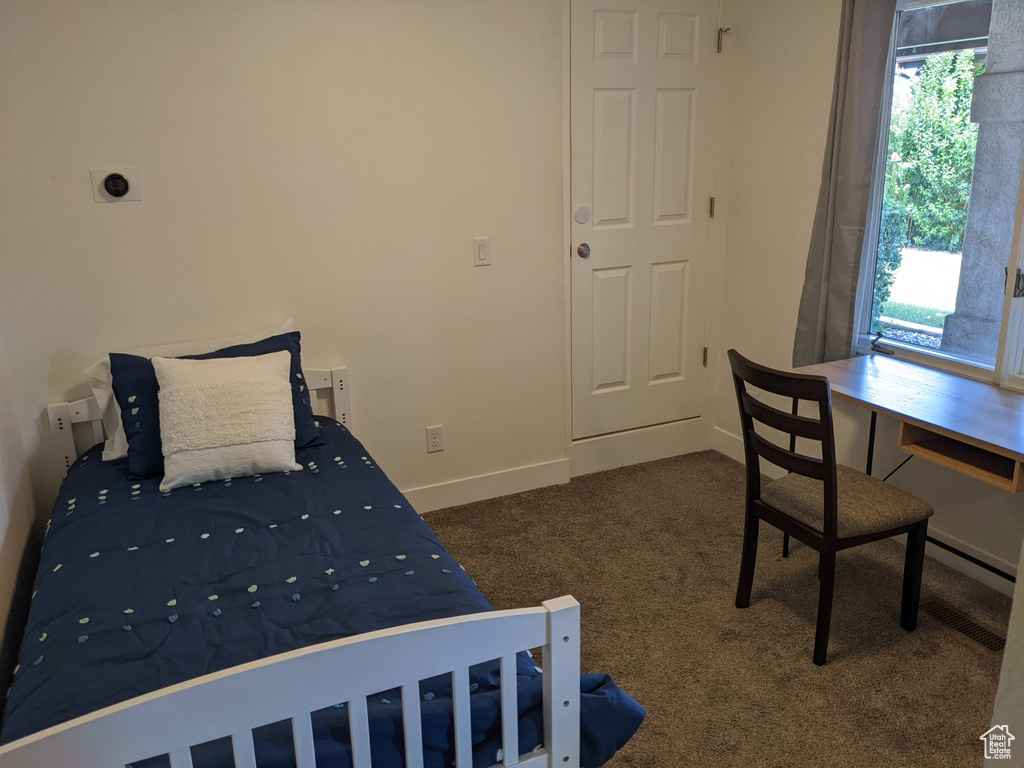 Bedroom featuring dark colored carpet and multiple windows