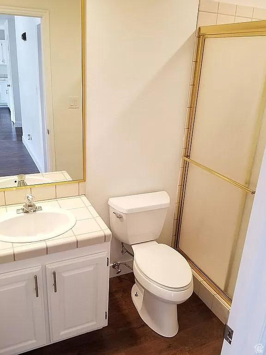 Bathroom with vanity, toilet, hardwood / wood-style flooring, and an enclosed shower