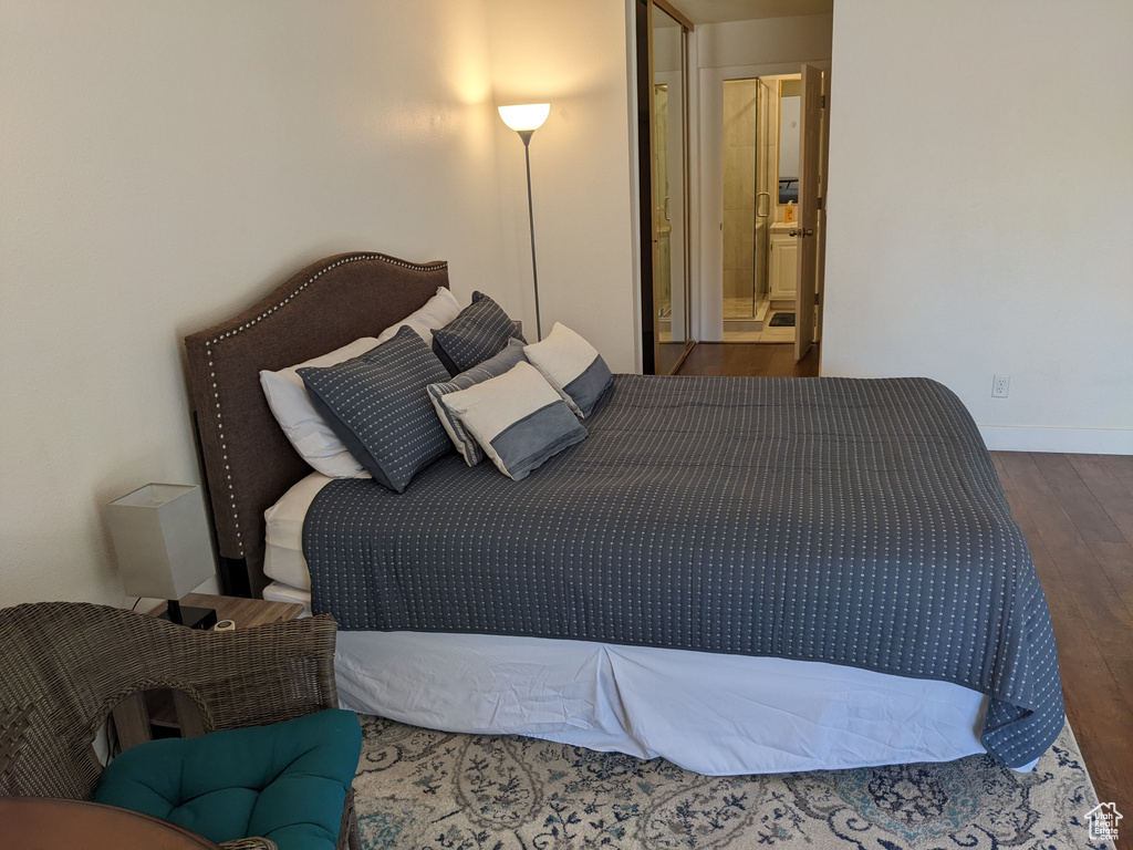 Bedroom with connected bathroom and dark wood-type flooring