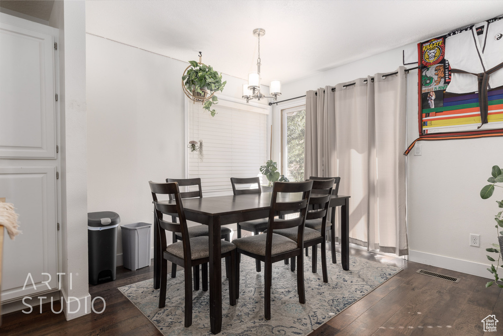 Dining area with dark wood-type flooring and a notable chandelier