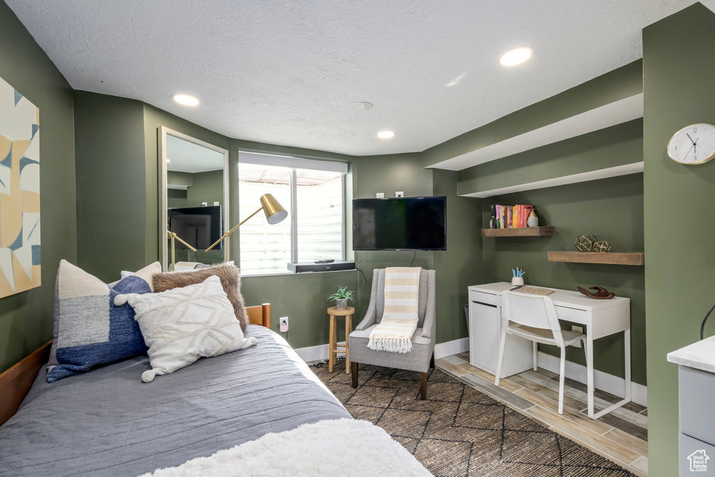 Bedroom with a textured ceiling and wood-type flooring