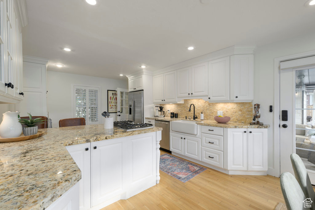 Kitchen featuring light hardwood / wood-style flooring, white cabinetry, sink, and stainless steel appliances