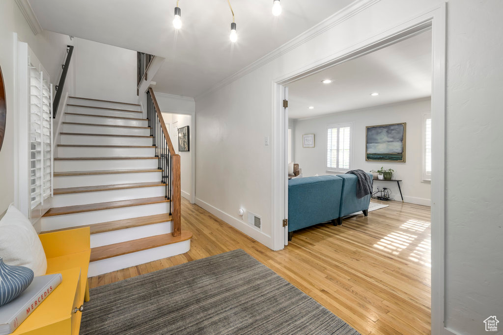 Stairs featuring wood-type flooring and ornamental molding