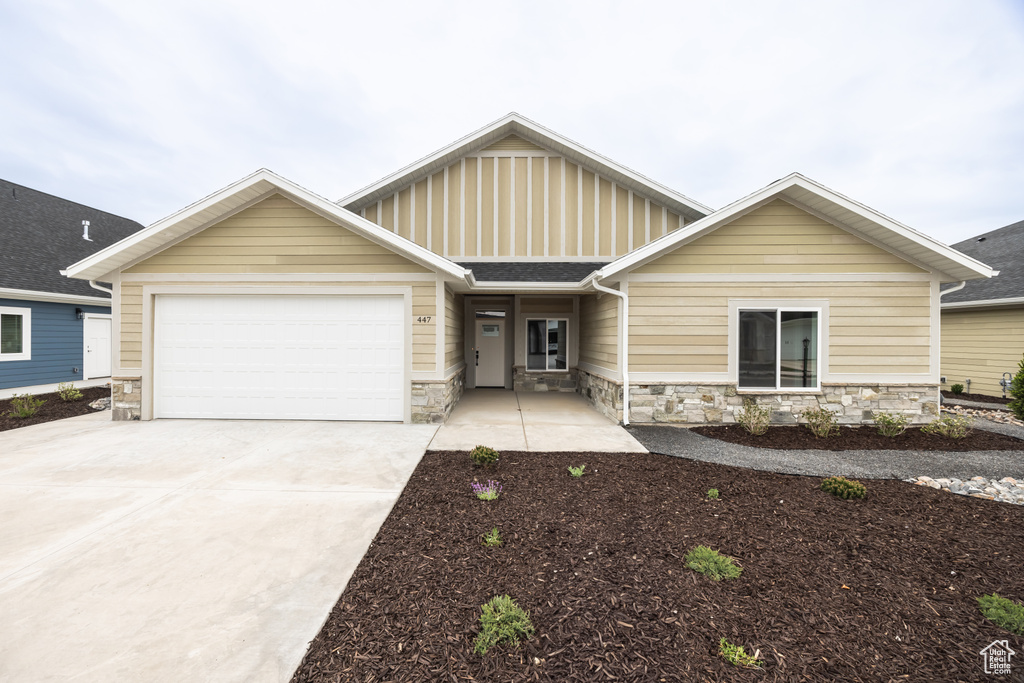 Craftsman-style home with stone siding, a garage, and driveway