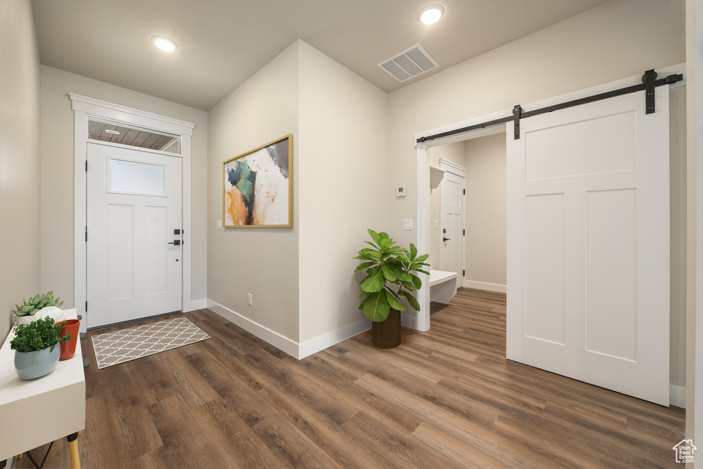 Entrance foyer featuring a barn door, baseboards, dark wood-style floors, and recessed lighting