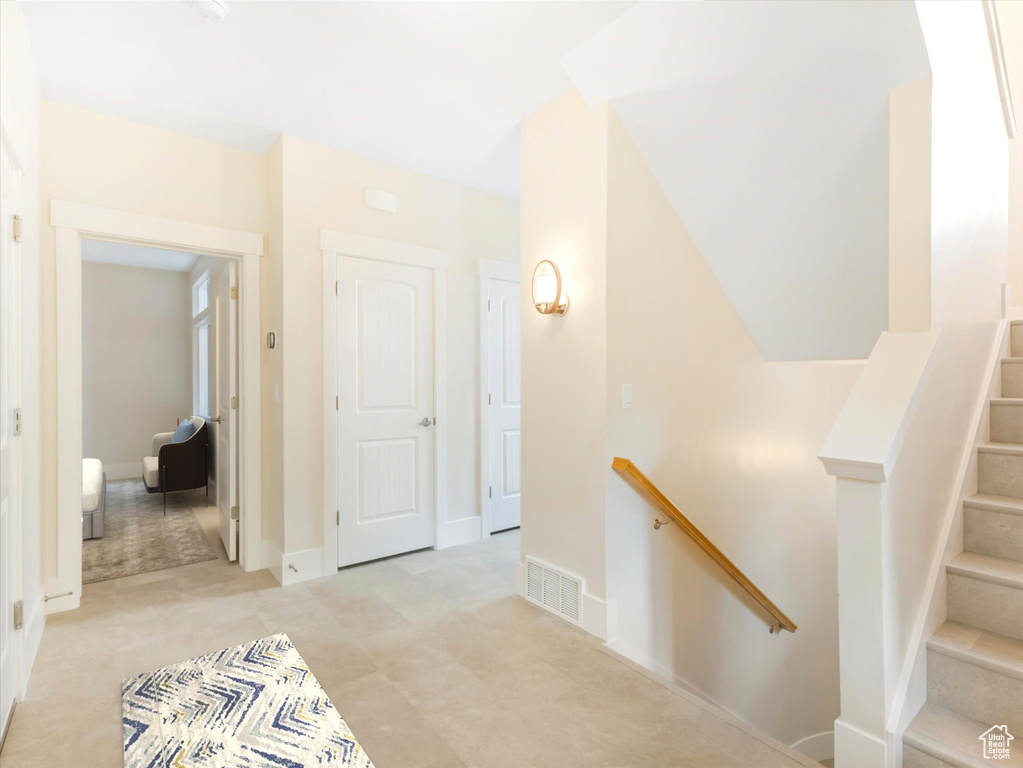 Corridor featuring baseboards, visible vents, and an upstairs landing