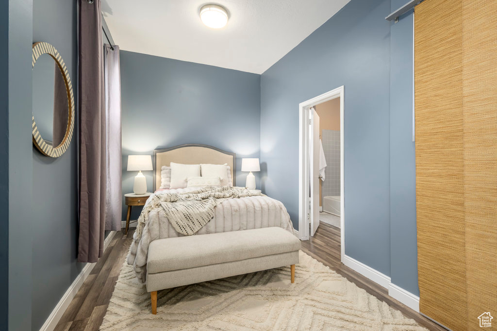 Bedroom featuring ensuite bath and dark wood-type flooring