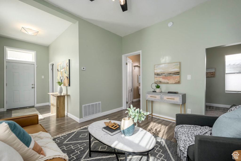 Living room featuring a wealth of natural light, vaulted ceiling, dark hardwood / wood-style floors, and ceiling fan