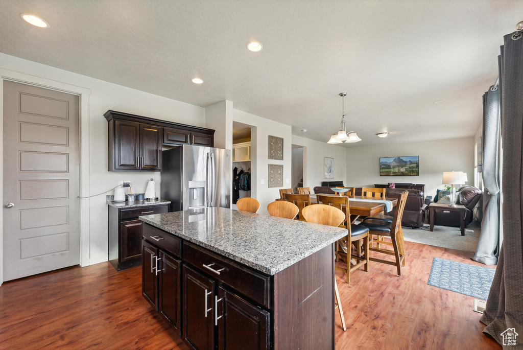 Kitchen featuring a kitchen island, dark brown cabinetry, stainless steel fridge with ice dispenser, a breakfast bar, and dark hardwood / wood-style floors