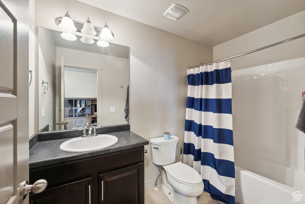 Full bathroom featuring vanity, toilet, a textured ceiling, and shower / tub combo