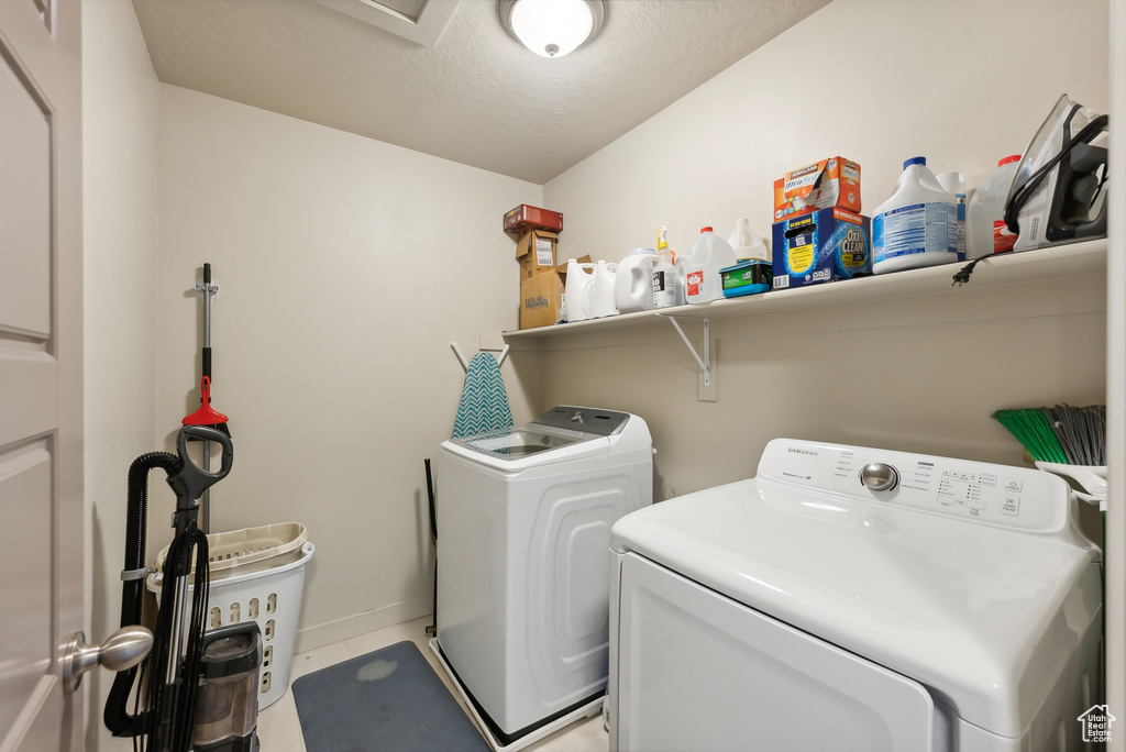 Clothes washing area featuring a textured ceiling and separate washer and dryer