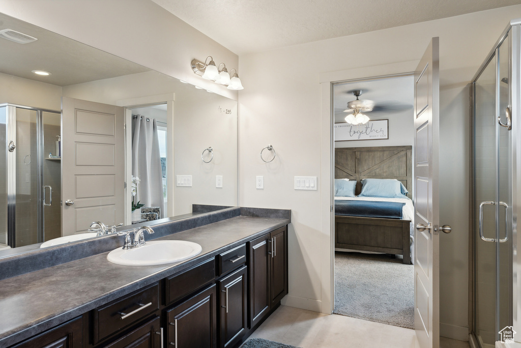 Bathroom with vanity, a shower with shower door, and ceiling fan