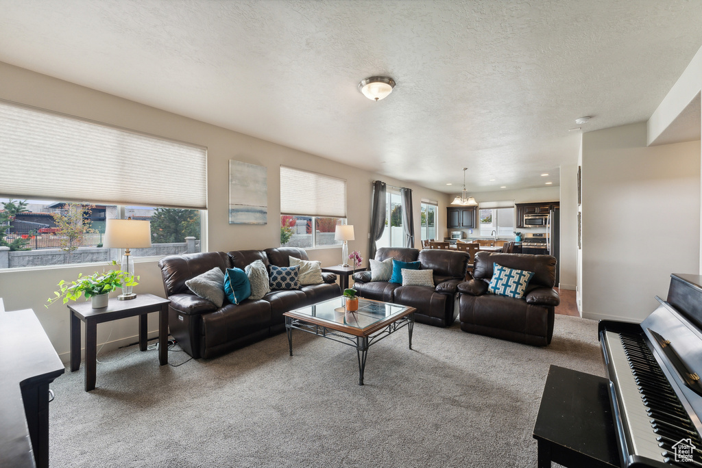 Living room featuring light carpet, an inviting chandelier, a textured ceiling, and a wealth of natural light