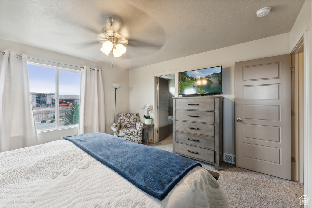 Carpeted bedroom featuring connected bathroom, ceiling fan, and a textured ceiling