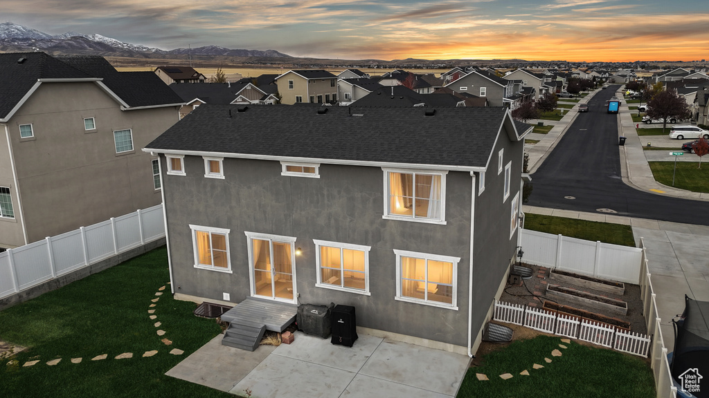 Back house at dusk with a mountain view and a lawn