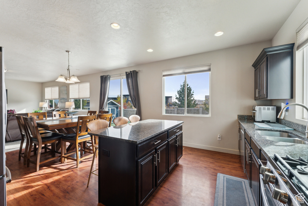 Kitchen with sink, a kitchen island, dark stone counters, and dark hardwood / wood-style flooring