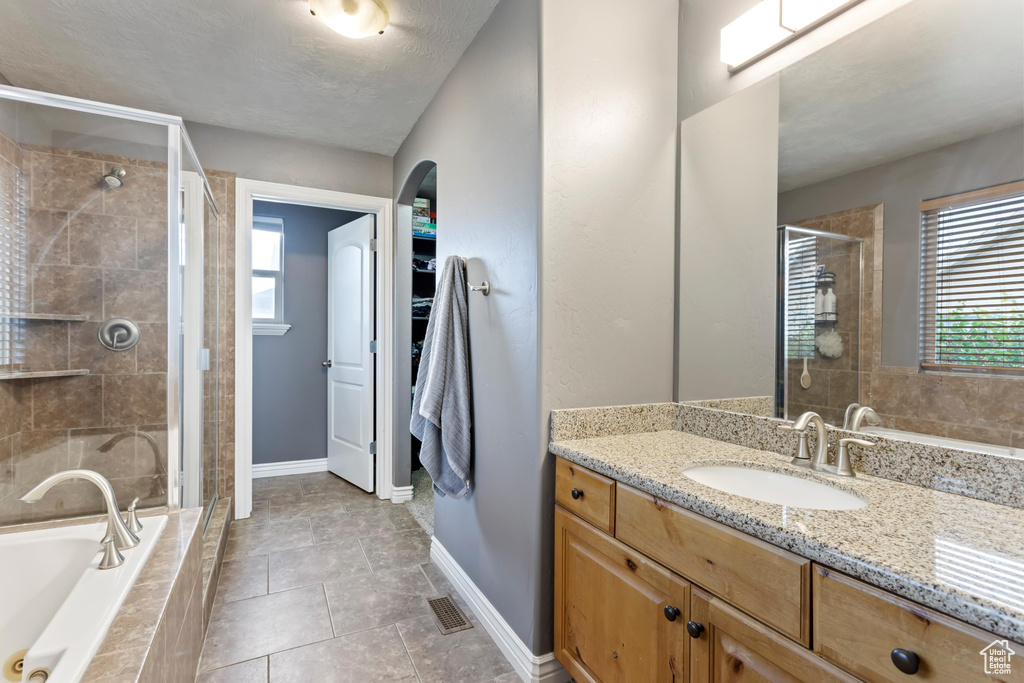 Bathroom with vanity, a textured ceiling, plus walk in shower, and tile patterned floors