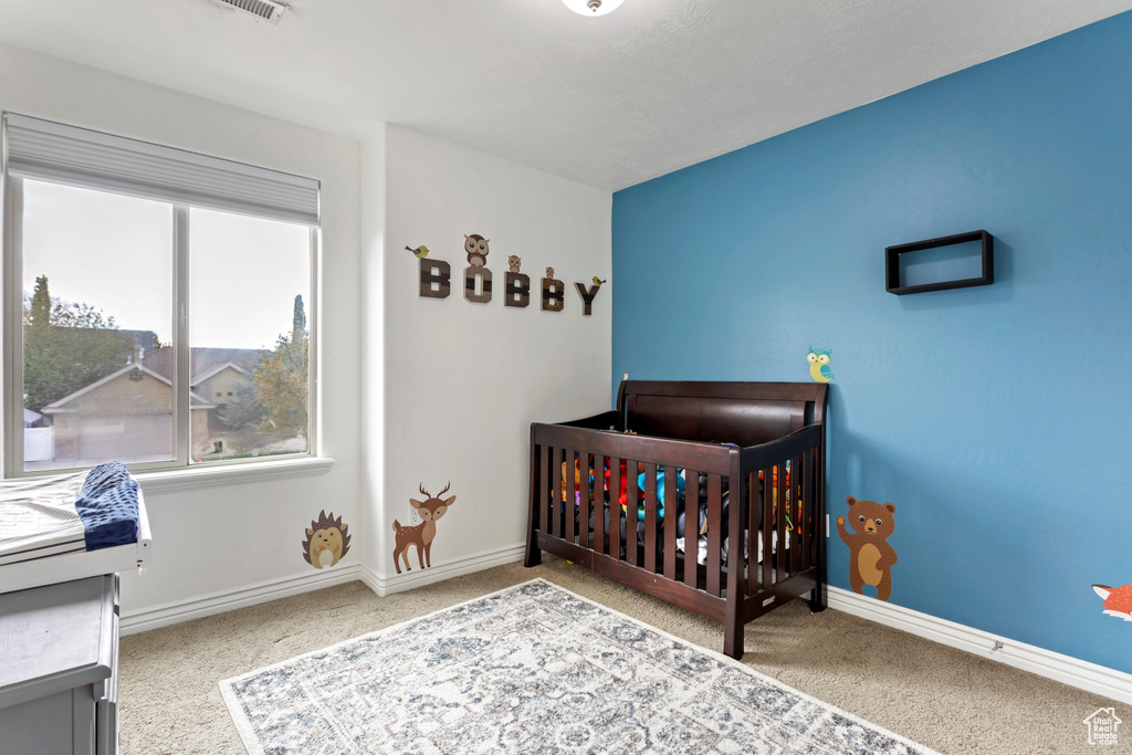 Bedroom featuring light carpet and a crib