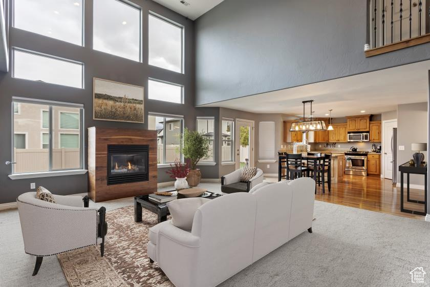 Living room with a towering ceiling, an inviting chandelier, and light hardwood / wood-style floors