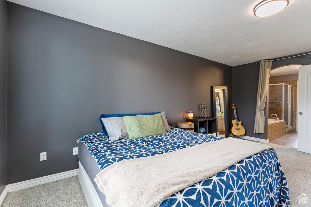 Bedroom featuring ensuite bath and light colored carpet