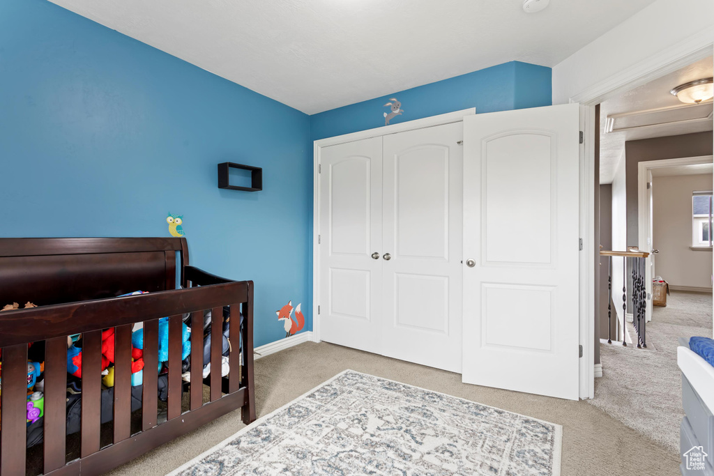 Bedroom featuring a closet, carpet, and a crib